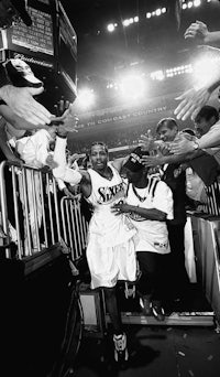 a black and white photo of a basketball player being embraced by fans